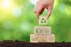 Hand stacking blocks with symbols related to sustainability